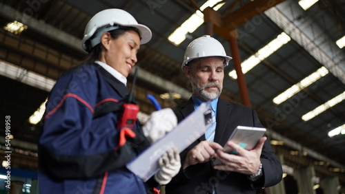 Factory manager or businessman and female engineer in factory. elegant man inspecting factory in industry plant background.