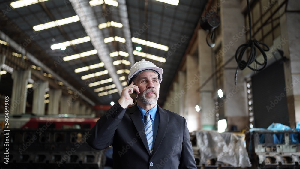 Factory manager or businessman owner in factory warehouse is talking on mobilephone. Business industry background.