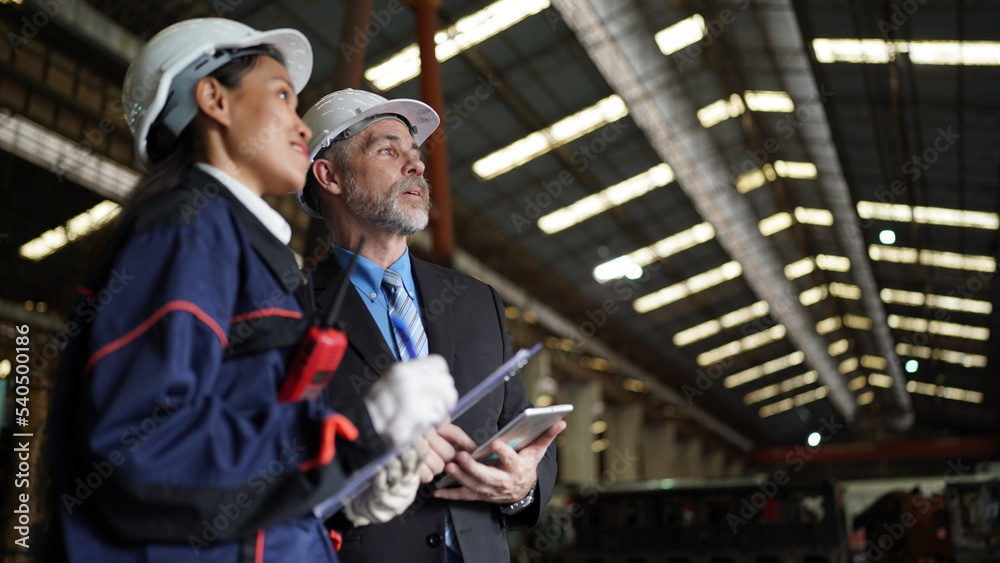 Factory manager or businessman and female engineer in factory. elegant man inspecting factory in industry plant background. Factory manager or businessman and female engineer in factory. elegant man inspecting factory in industry plant background.