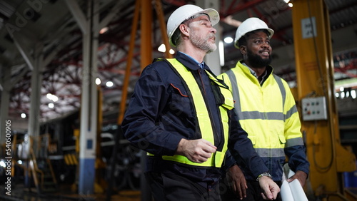 Portrait of engineer and apprentice in workshop of railway engineering facility