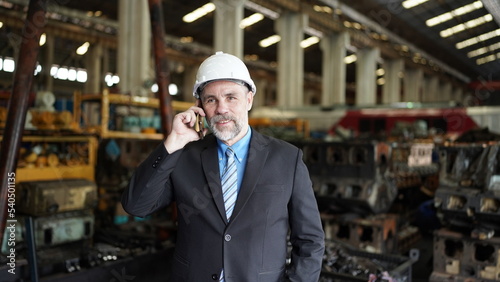 Factory manager or businessman in factory warehouse is talking on mobilephone. Factory indusrty Business.
