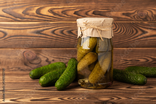 A jar of pickles. Canned cucumbers in a jar on a brown wooden background. Collection of vegetables. Pickled jars. Stocks for the winter. home preservation. pickles. Copy space