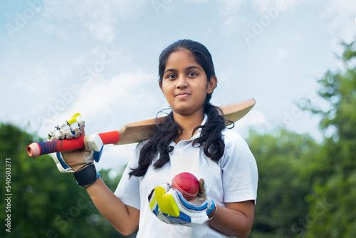 Portrait Of A Female Cricketer Holding A Cricket Bat And A Ball 