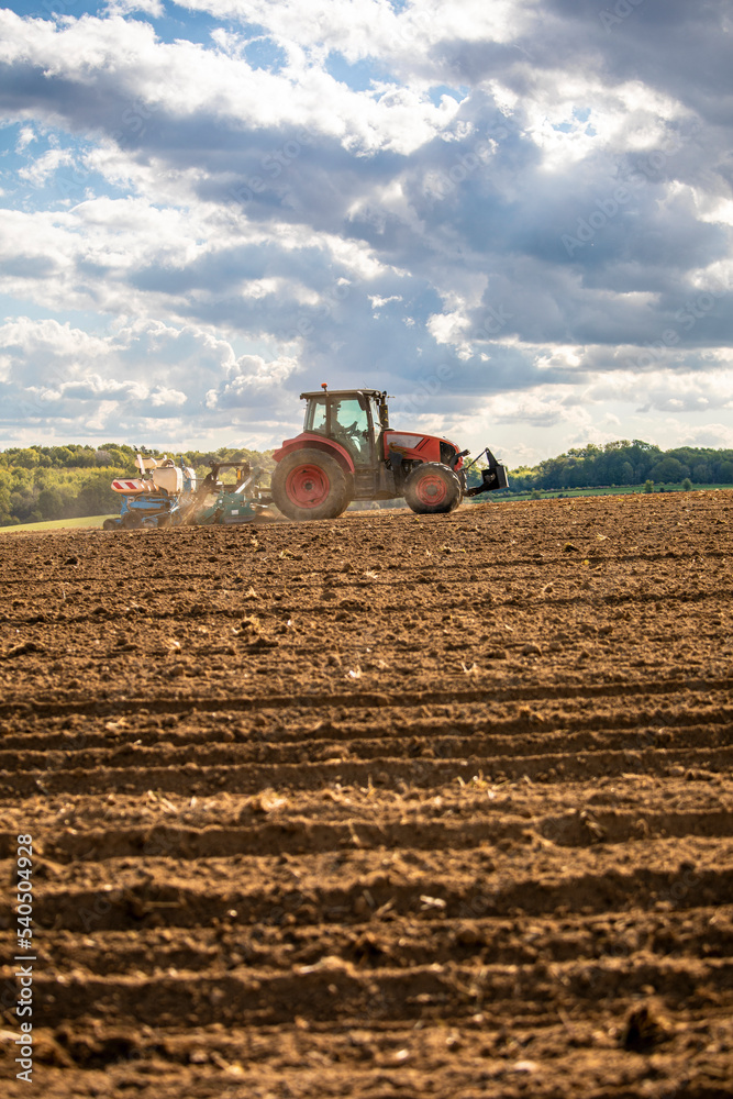 Obraz premium Agriculteur au volant de son tracteur labourant son champ de terre au printemps.