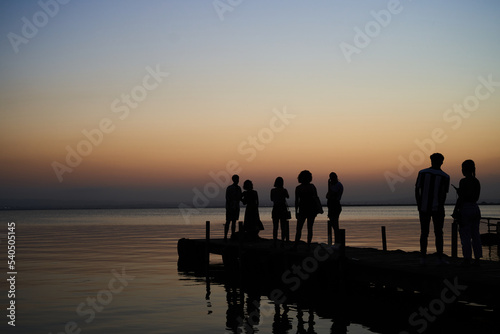 Tourists waiting to take pictures at wooden dock in Albufera lake in Valencia at sunset