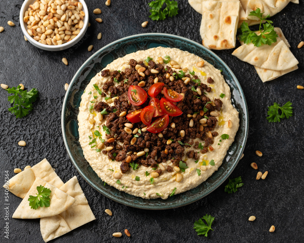 Hummus with spiced ground beef, olive oil, tomatoes and toasted pine nuts