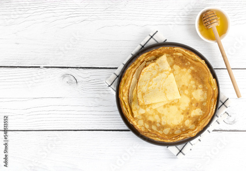Fényképezés French crepes, pancakes or Russian blini with honey on a white wooden background