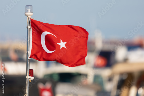 Turkish flag, on a red background white star and moon. Flag flies in the wind against the backdrop of the Bosporus and views of Istanbul