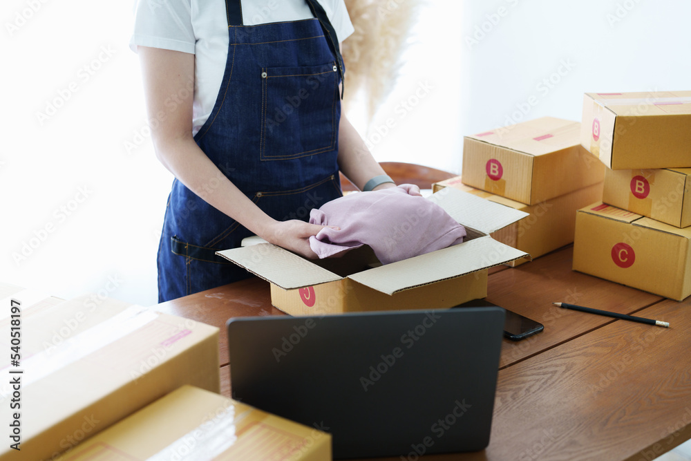 Fototapeta premium Starting small business entrepreneur of independent Asian woman smiling with cheerful success of online marketing package box items and SME delivery concept