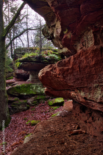 Red rock wall leading to rock formation on a winter day in the Palatinate Forest of Germany.