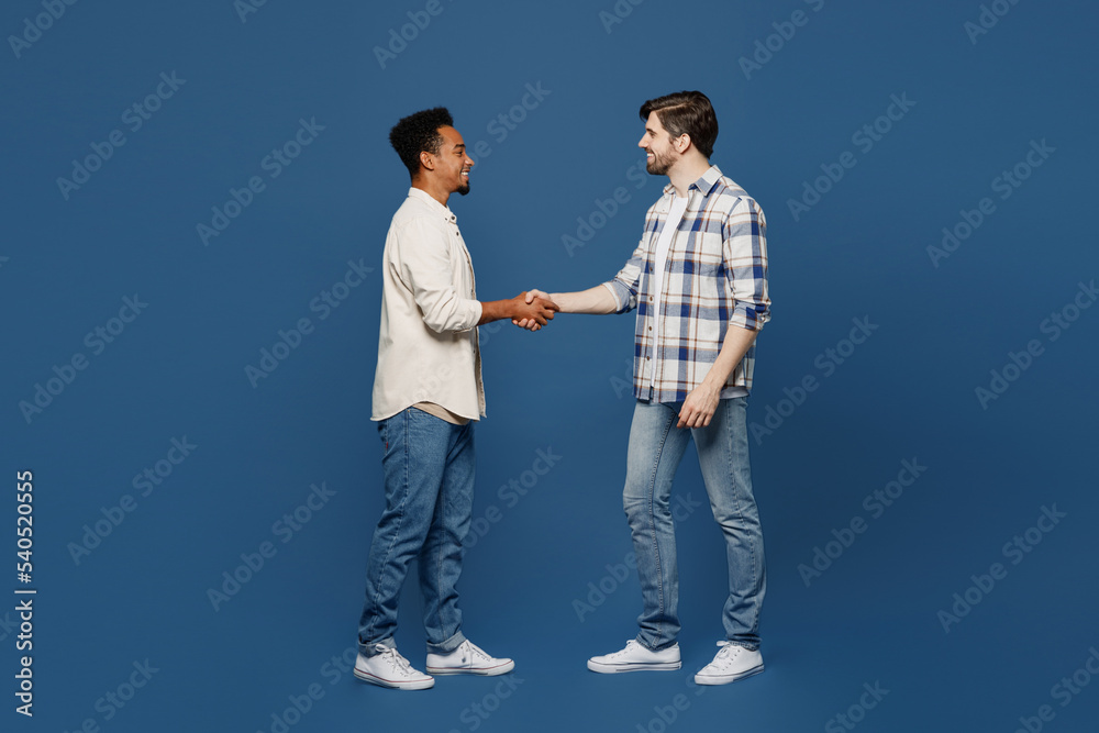 Foto Stock Full body young side view two friends fun men wear white casual  shirts looking camera together shaking hands meeting each other isolated  plain dark royal navy blue background People lifestyle