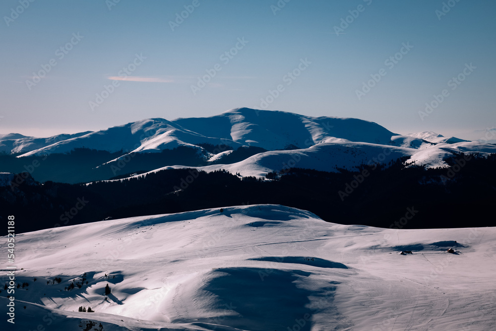 Panoramic view over the ski slope Poiana Brasov ski resort in Transylvania, Pine forest covered in snow on winter season,Mountain landscape in winter with the Bucegi Mountains in the background. Panoramic view over the ski slope Poiana Brasov ski resort in Transylvania, Pine forest covered in snow on winter season,Mountain landscape in winter with the Bucegi Mountains in the background.