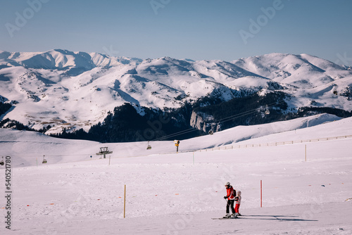 Panoramic view over the ski slope Poiana Brasov ski resort in Transylvania, Pine forest covered in snow on winter season,Mountain landscape in winter with the Bucegi Mountains in the background. photo