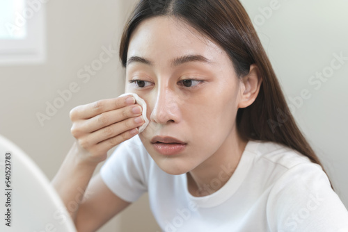 Woman using cotton pad wipe to clean cosmetic on her face