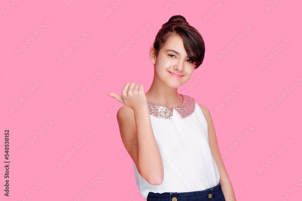 Brunette teen girl pointing back to the pink background Brunette teen girl pointing back to the pink background