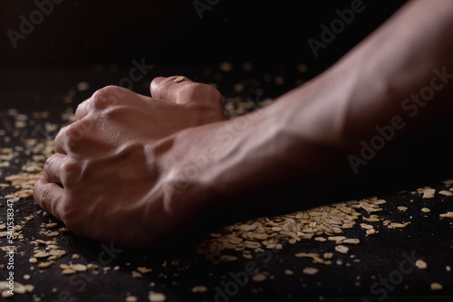 Male hands pouring muesli on a black background