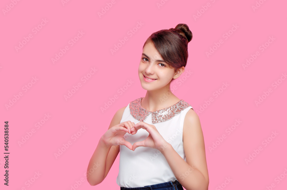 Smiling brunette girl making heart with hands isolated on pink background Smiling brunette girl making heart with hands isolated on pink background
