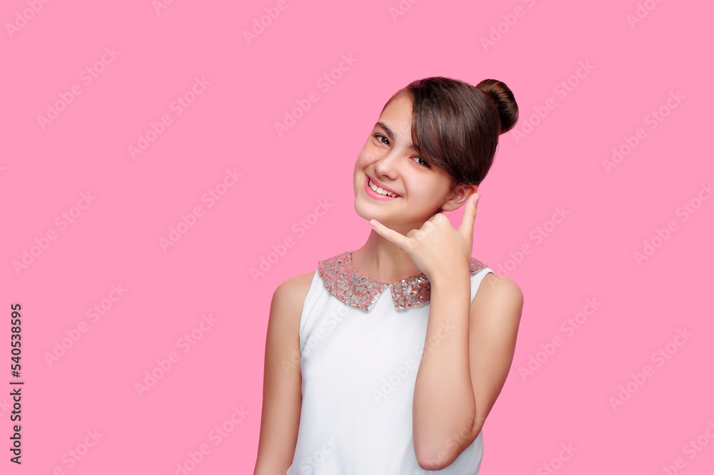 Smiling girl against pink background showing call me gesture Smiling girl against pink background showing call me gesture