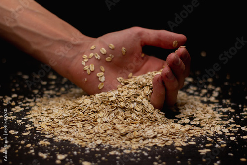 Male hands pouring muesli on a black background