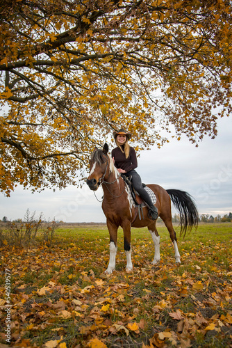 cowboy girl in hat riding horse in autumn field