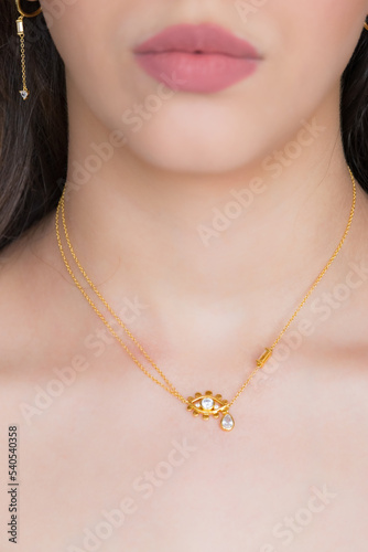 Young woman wearing a golden necklace and golden earrings. Beautiful valentine's gift.