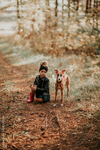 Obraz na płótnie Mała modelka z psem whippet w lesie w salonie