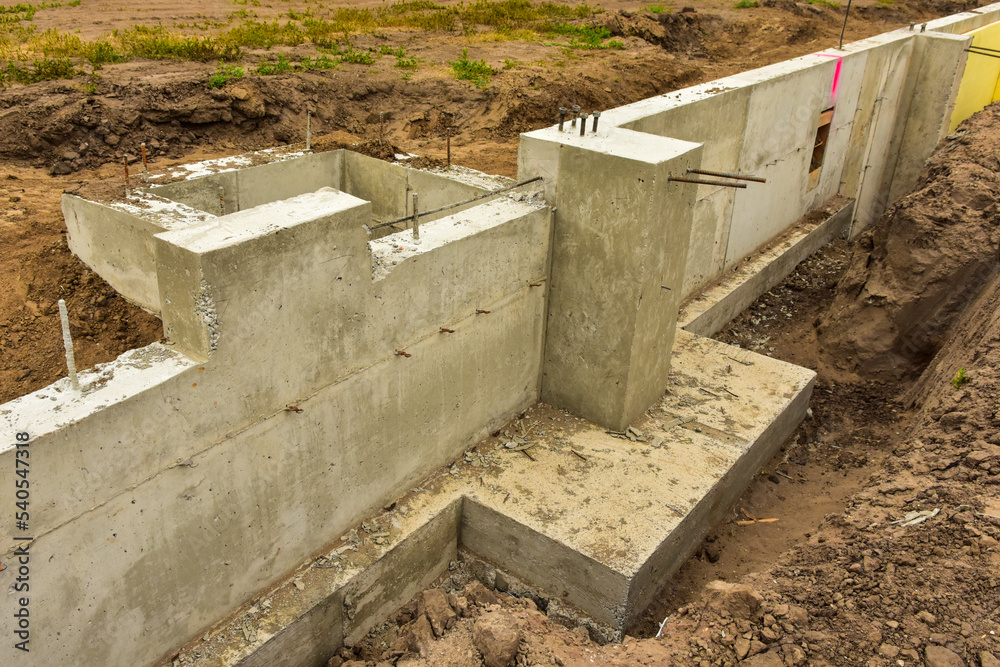 Concrete footings and foundation with anchor bolts ready for further construction.
