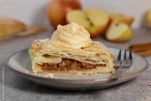 piece of an apple strudel roll with cinnamon and ice cream on top