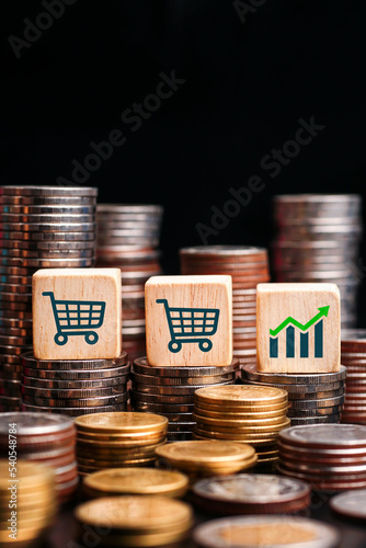 wooden block with the graph icon on the wooden block supermarket cart icon sale target on the background stacks coins, improve sale income, strategy marketing concept.                 