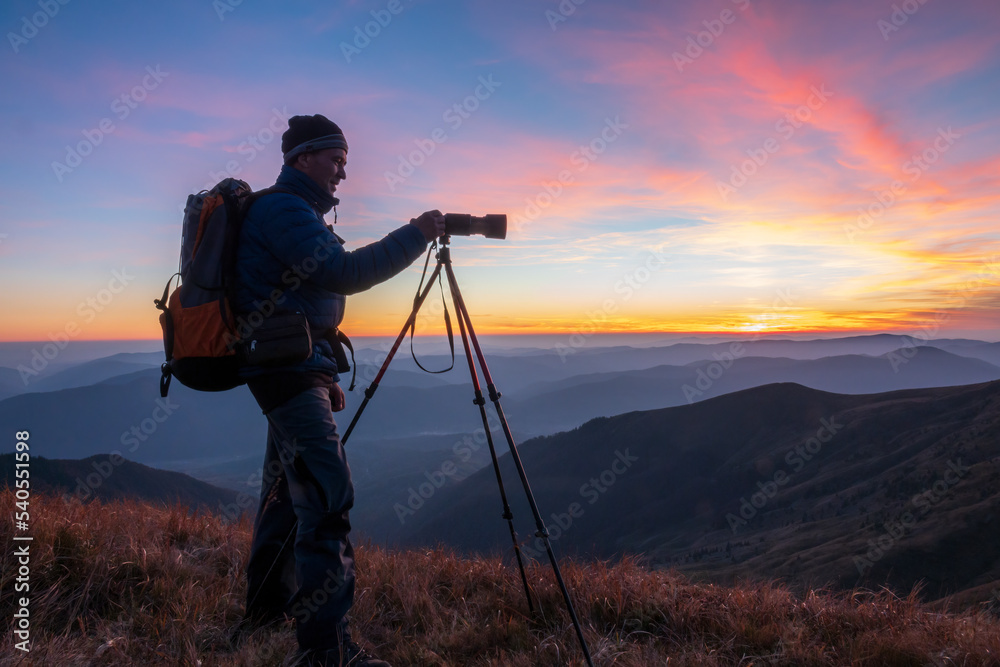 Landscape photographer with the tripod at the sunset