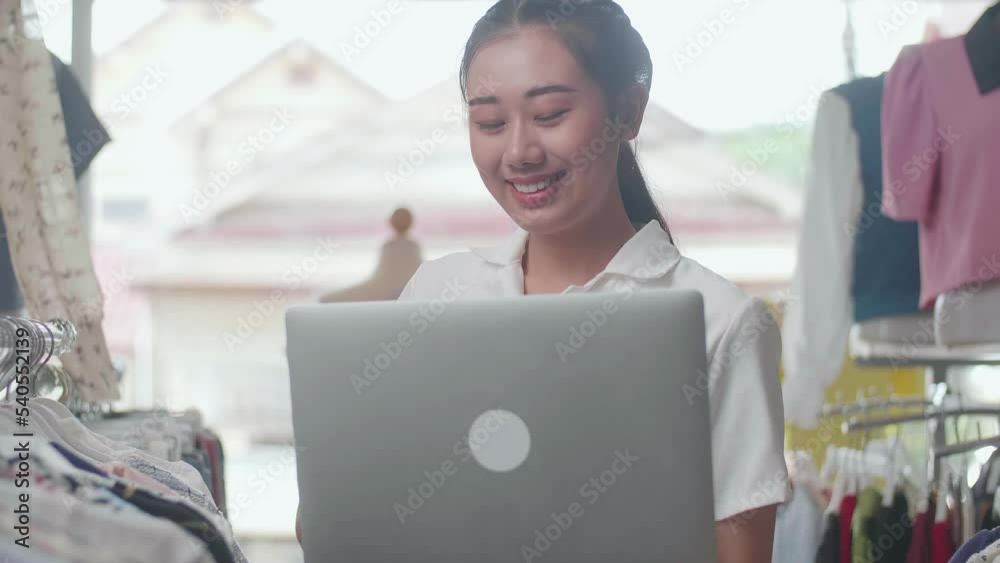 Close Up Of Asian Female Owner Of Clothing Store Smiling To The Camera While Using A Laptop To Check Stock On Rails
Close Up Of Asian Female Owner Of Clothing Store Smiling To The Camera While Using A Laptop To Check Stock On Rails
