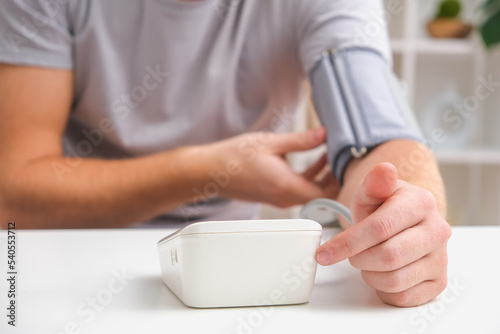 A man measures blood pressure with a white electric tonometer lying on a white table. Measurement of pressure and pulse. The concept of a healthy lifestyle.