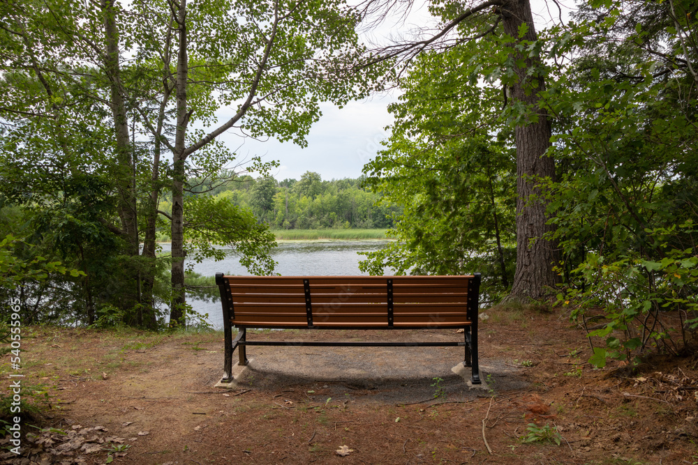 an empty park bench beside a river an empty park bench beside a river