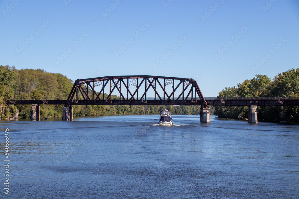 Fototapeta premium Boats passing under a rusted metal bridge on the Erie Canal
