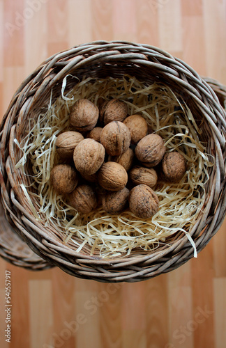 Whole Walnuts In A Wood Shavings Inside A Wicker Basket On A Wooden Planks Background For Vertical Story

