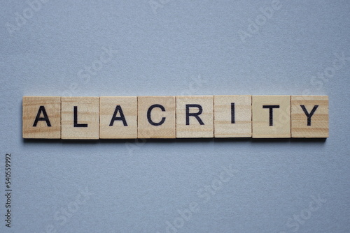 text the word alacrity from brown wooden small letters with black font on an gray table