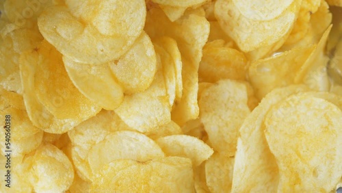 A woman's hand takes one crispy snack. A pile of unhealthy food lies on the table. People take chips, the video is shot close-up.