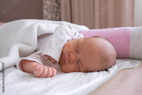 cute little newborn baby girl peacefully sleeps in the nursery on a white cotton bed