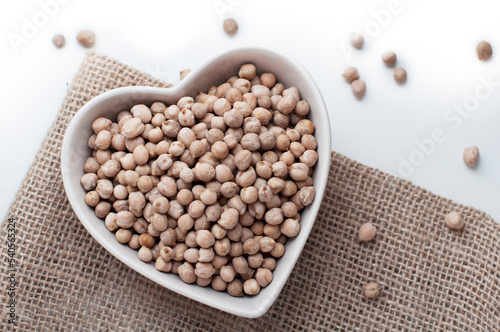 Chickpeas in a heart shaped bowl on canvas and white background