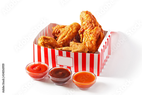 Fotografie Crispy southern fried chicken in a red and white carry-out box with sauces on a white background with copy space