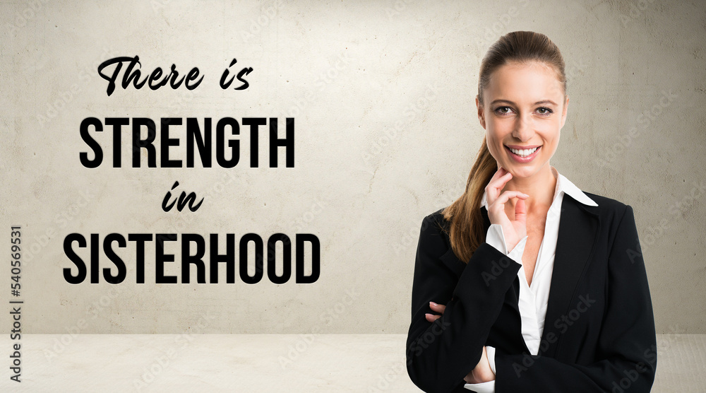 smiling businesswoman in front of a wall with the message THERE IS STRENGTH IN SISTERHOOD smiling businesswoman in front of a wall with the message THERE IS STRENGTH IN SISTERHOOD