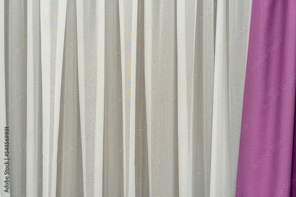 Obraz premium Delicate curtains in a new cozy apartment. Curtains cover the windows from the intrusive glances of neighbors and passers-by. The textile background is beige and pink.