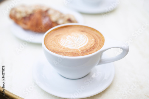 A cup of cappuccino and a croissant