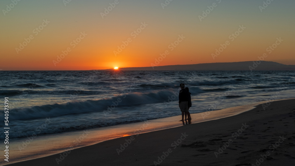 Romantic couple walking on the beach at sunset