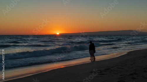Romantic couple walking on the beach at sunset