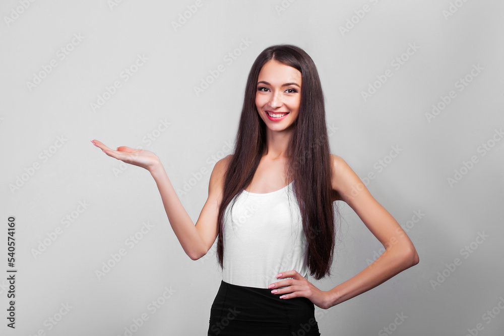 Smiling business woman pointing up and looking at the camera over gray background Smiling business woman pointing up and looking at the camera over gray background
