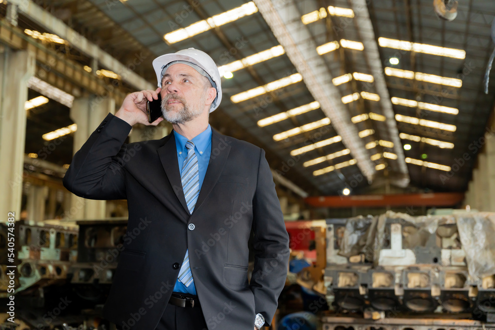 A businessman checks on-site maintenance work at an old factory for train rehearsals. talking on the phone with customers or employees A businessman checks on-site maintenance work at an old factory for train rehearsals. talking on the phone with customers or employees