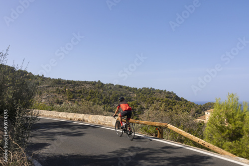 Hombre practicando ciclismo en Mallorca. Ciclista mirando al mar mientras rueda por una carretera de las monta  as de la Serra de Tramuntana de Mallorca  Islas Baleares  Espa  a .