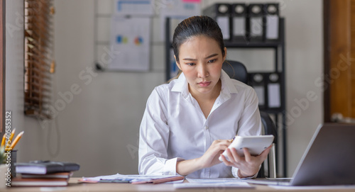 Young business Asian woman stressed while working, Tired asian businesswoman with headache at home office, payment stressed and confused by calculate expense from invoice or bill tax.
