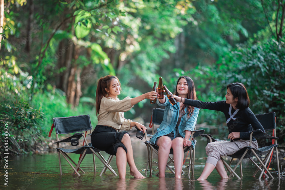 Young women sitting and drink beverage  while camping in forest